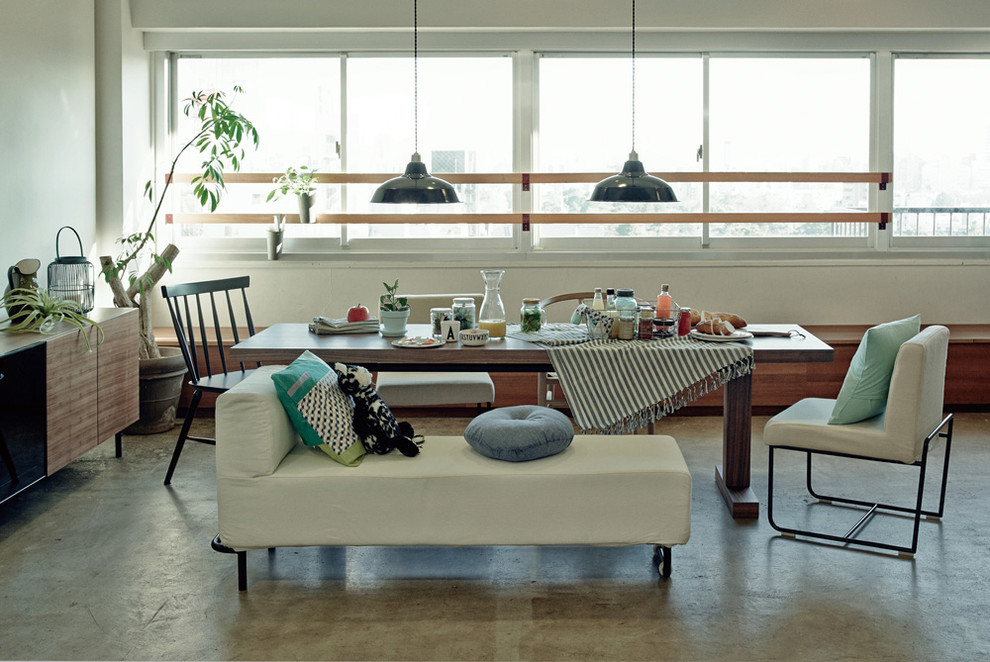 Esempio di una sala da pranzo aperta verso il soggiorno industriale con pareti bianche, pavimento in cemento e pavimento grigio