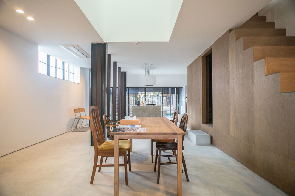 Immagine di una sala da pranzo aperta verso il soggiorno etnica con pareti multicolore, pavimento in cemento e pavimento grigio