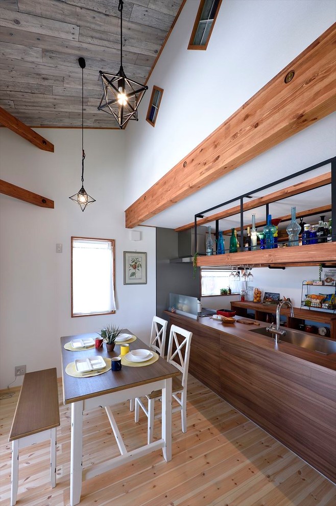 Idee per una sala da pranzo aperta verso il soggiorno etnica con pareti bianche, parquet chiaro e pavimento marrone