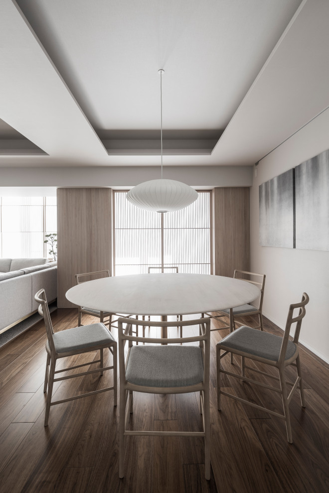 Cette photo montre une salle à manger ouverte sur le salon moderne de taille moyenne avec un sol en contreplaqué, un sol marron et un mur gris.