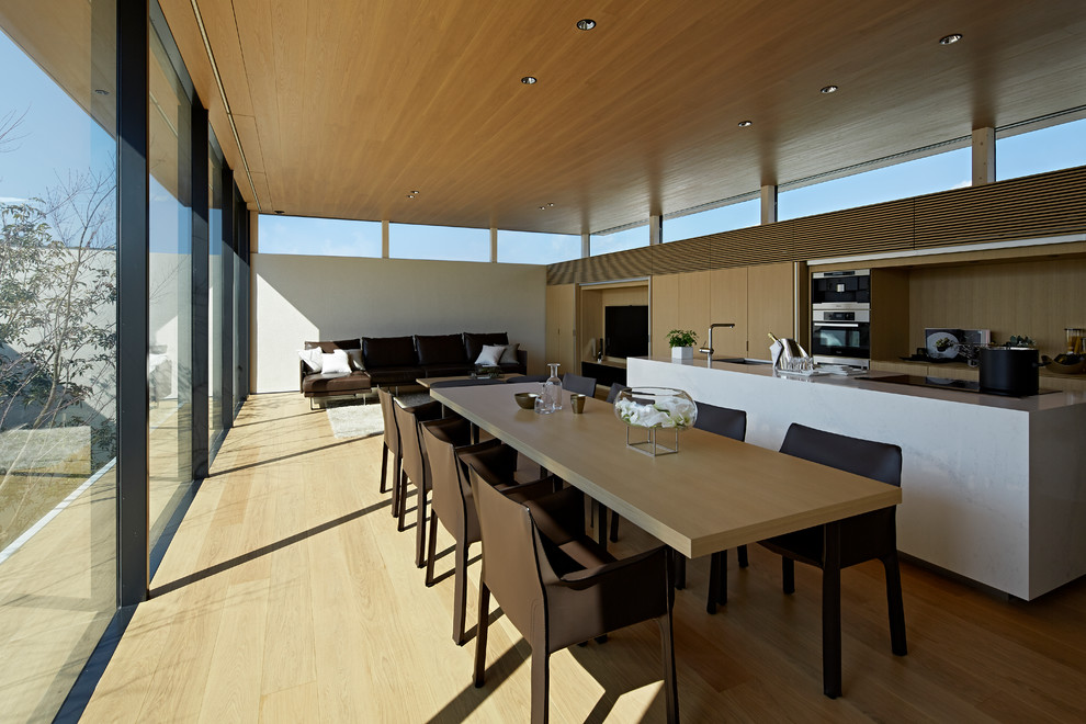 Modern open plan dining room in Tokyo with white walls, beige floors and plywood flooring.