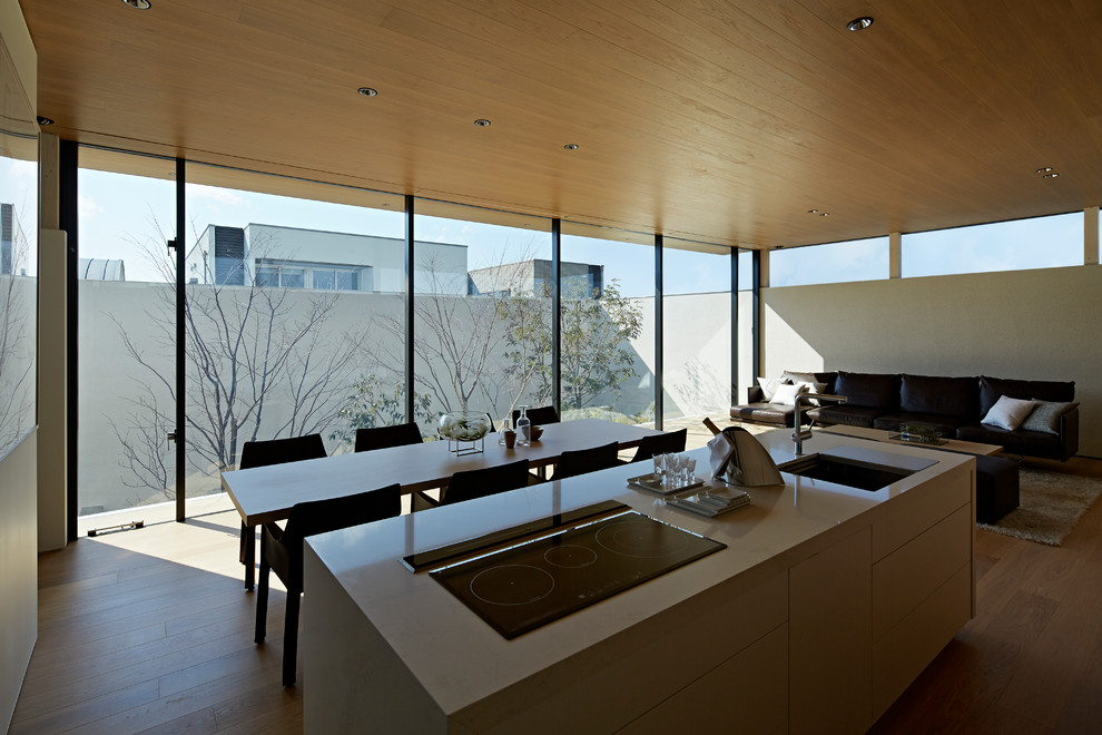 Cette image montre une salle à manger ouverte sur le salon minimaliste avec un mur blanc, un sol en contreplaqué et un sol beige.