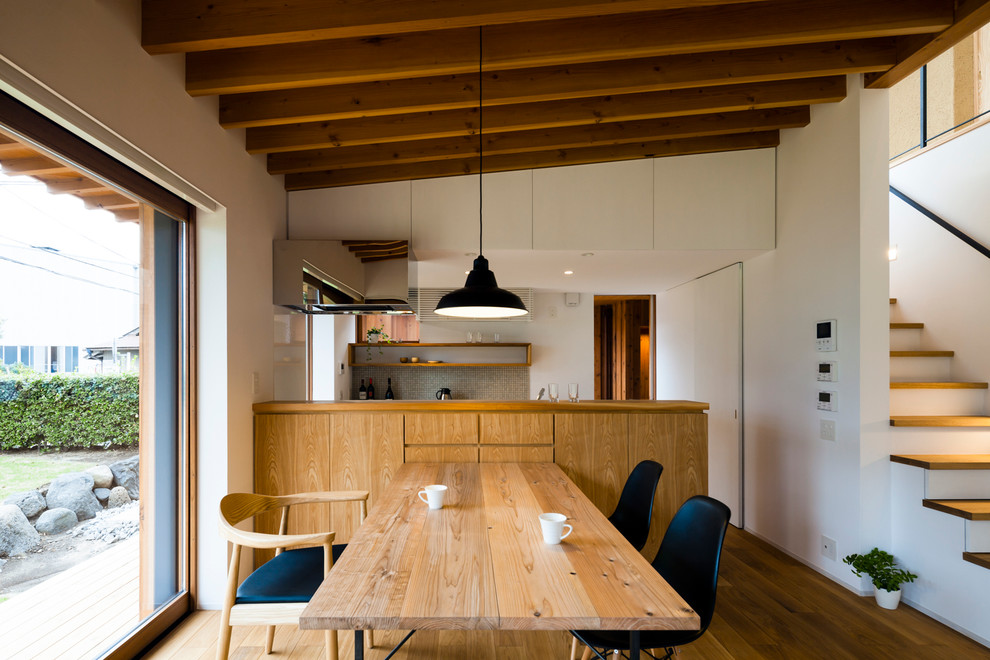 Modern inredning av ett litet kök med matplats, med vita väggar och mellanmörkt trägolv