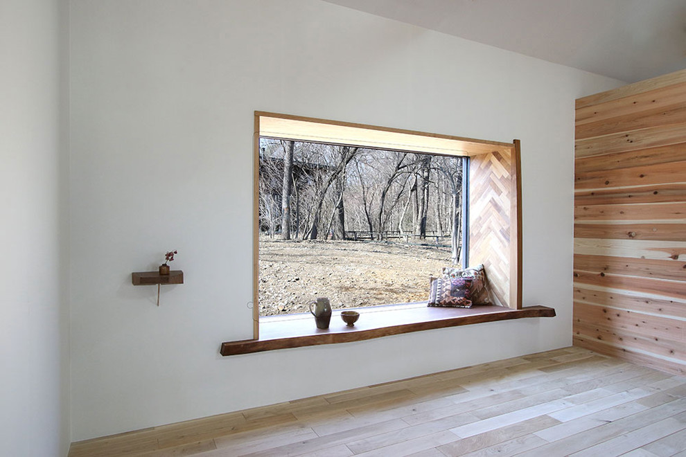 Aménagement d'une salle à manger ouverte sur le salon montagne avec un mur blanc, parquet clair, un poêle à bois et un manteau de cheminée en béton.