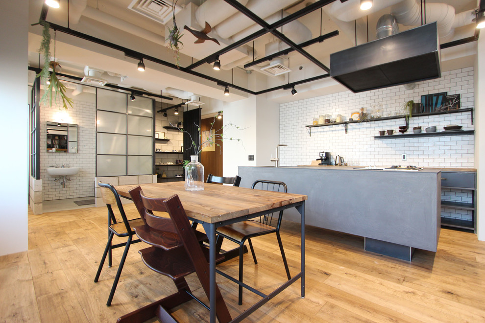 This is an example of an urban dining room in Tokyo with white walls and light hardwood flooring.