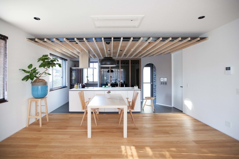 Foto di una grande sala da pranzo aperta verso il soggiorno minimalista con pavimento nero e pareti bianche
