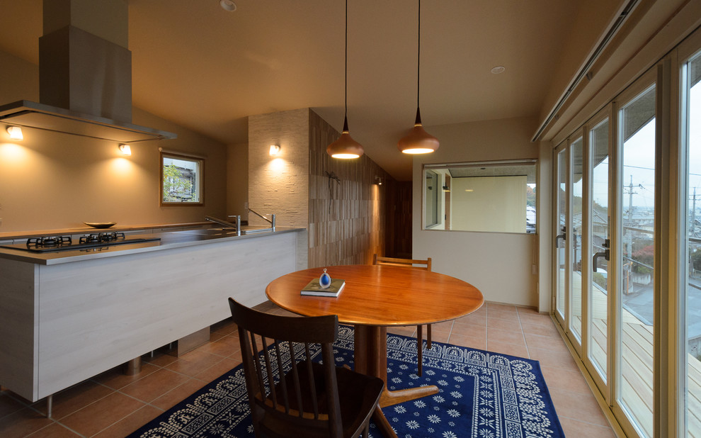 Стильный дизайн: столовая в стиле модернизм с разноцветными стенами, полом из терракотовой плитки и коричневым полом - последний тренд