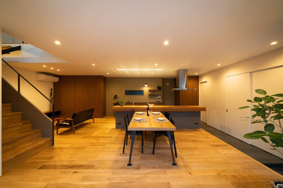 Exemple d'une salle à manger tendance avec un mur blanc et un sol en bois brun.