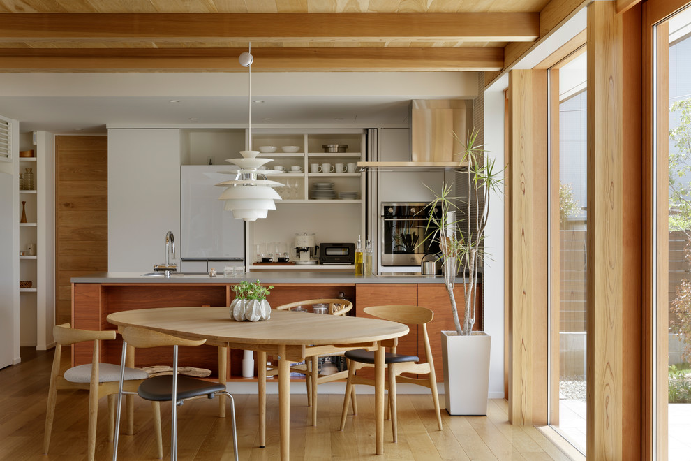 Ejemplo de comedor de cocina nórdico con paredes blancas, suelo de madera en tonos medios y suelo marrón