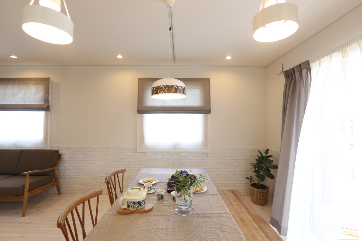 Aménagement d'une salle à manger ouverte sur le salon scandinave avec un mur blanc, parquet clair et un sol blanc.
