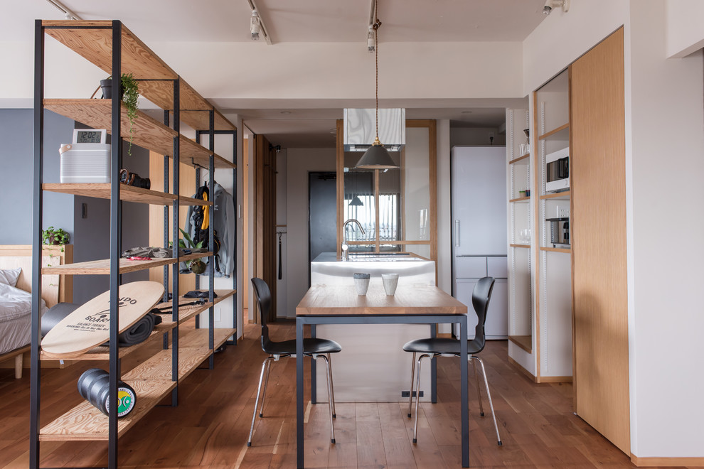 Idee per una piccola sala da pranzo aperta verso il soggiorno industriale con pareti bianche, pavimento in legno massello medio e pavimento marrone