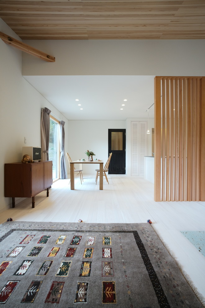 Offenes Modernes Esszimmer mit weißer Wandfarbe, hellem Holzboden, Kaminofen, Kaminumrandung aus Stein und weißem Boden in Sonstige