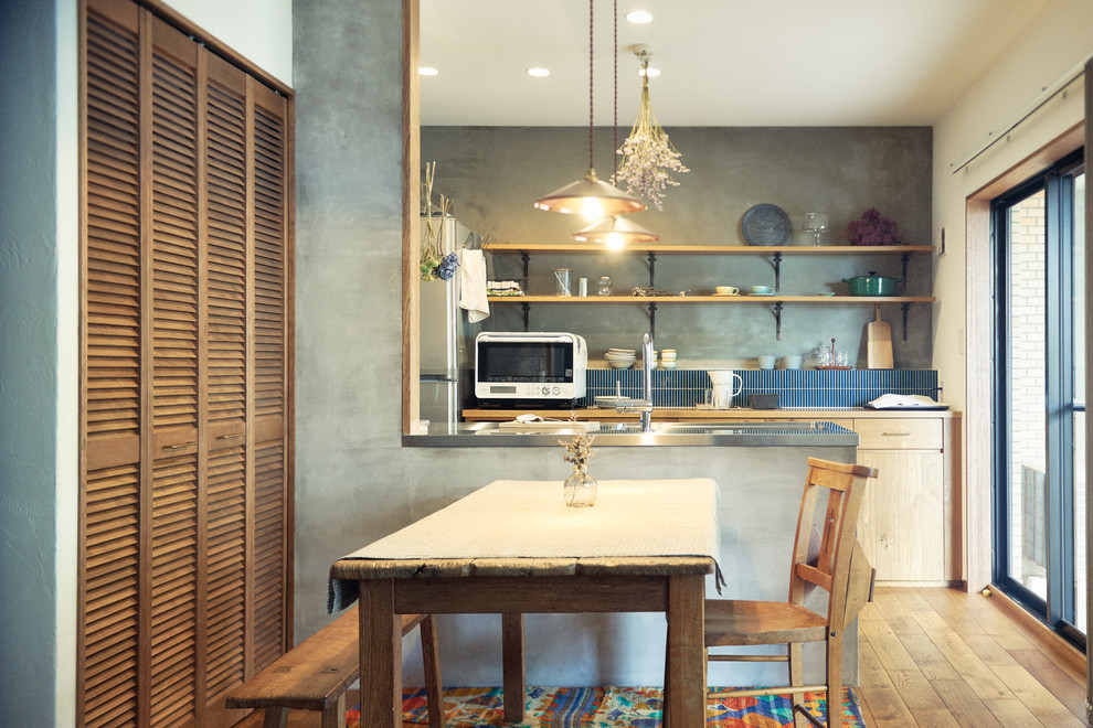Exemple d'une petite salle à manger ouverte sur la cuisine nature avec un mur gris et un sol en bois brun.