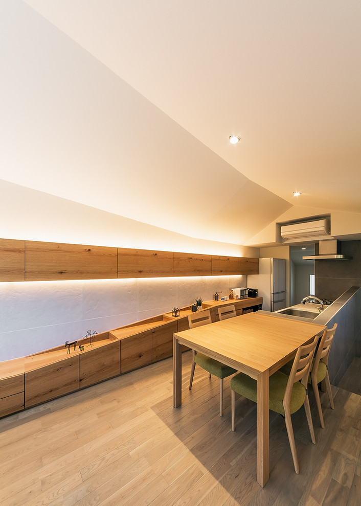 Esempio di una sala da pranzo aperta verso la cucina minimal con pareti bianche, pavimento in legno verniciato e pavimento beige