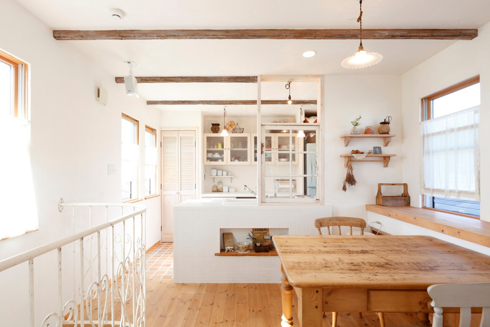 Réalisation d'une petite salle à manger ouverte sur la cuisine champêtre avec un mur blanc, parquet clair, aucune cheminée, un sol beige et poutres apparentes.
