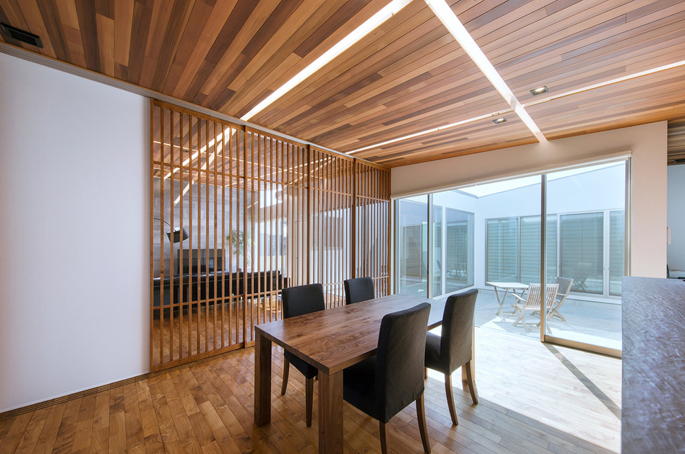Ispirazione per una sala da pranzo aperta verso il soggiorno moderna con pareti bianche, pavimento in legno massello medio e pavimento marrone