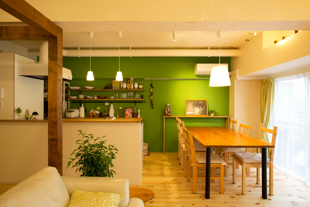 Immagine di una sala da pranzo industriale con pareti verdi, parquet chiaro e pavimento marrone
