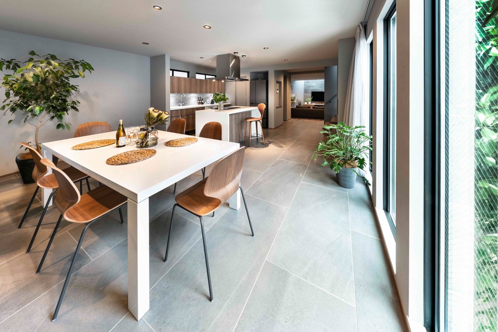 Immagine di una sala da pranzo aperta verso la cucina minimalista di medie dimensioni con pareti grigie, pavimento in vinile, pavimento grigio e camino ad angolo