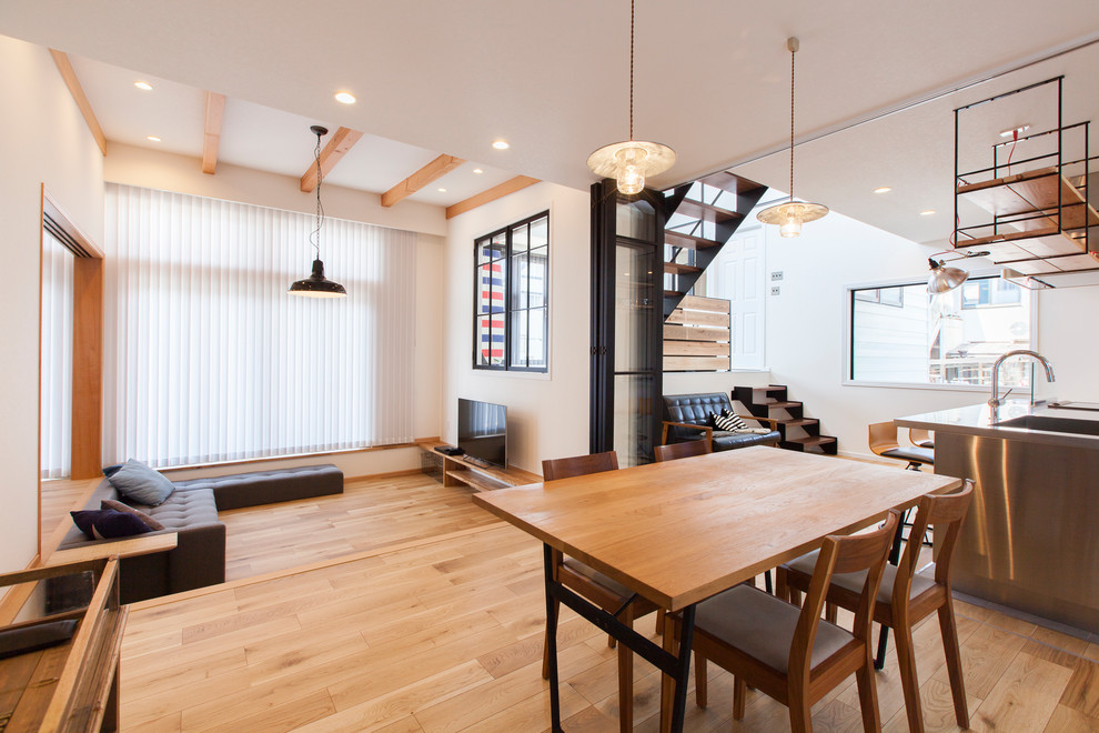 Aménagement d'une salle à manger ouverte sur le salon contemporaine avec un mur blanc, parquet clair et un sol marron.