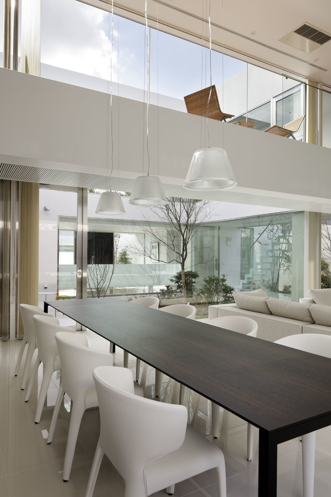 Immagine di una grande sala da pranzo aperta verso il soggiorno minimalista con pareti bianche e nessun camino