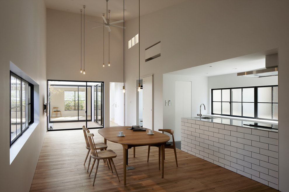 Inspiration pour une salle à manger ouverte sur la cuisine asiatique avec un mur blanc, un sol en bois brun et un sol marron.