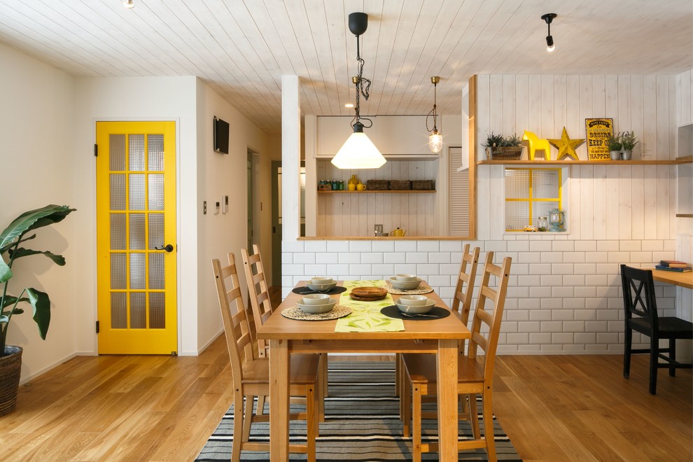Cette image montre une petite salle à manger ouverte sur la cuisine rustique avec un mur blanc et parquet clair.