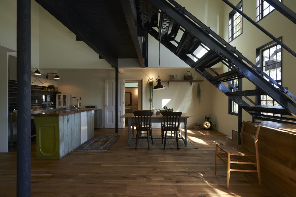 Cette photo montre une salle à manger ouverte sur le salon industrielle avec un mur blanc et un sol en bois brun.