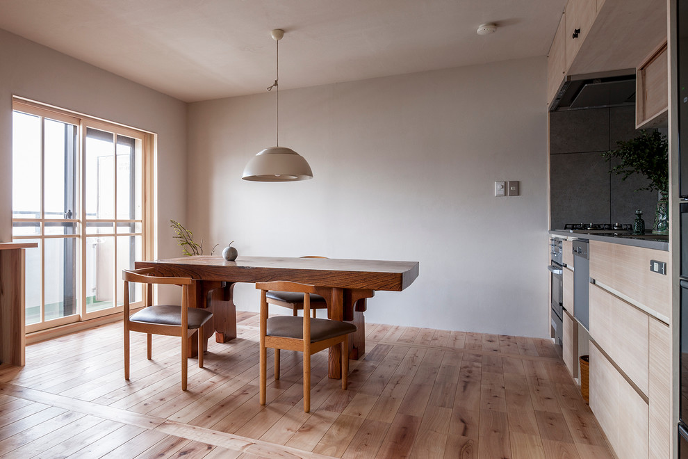 Esempio di una sala da pranzo aperta verso la cucina etnica di medie dimensioni con pareti bianche, pavimento in legno massello medio e pavimento marrone