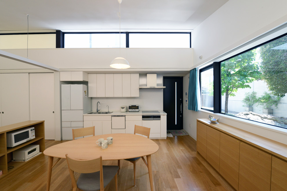 Idee per una sala da pranzo aperta verso il soggiorno moderna con pareti bianche, pavimento in legno massello medio e pavimento marrone