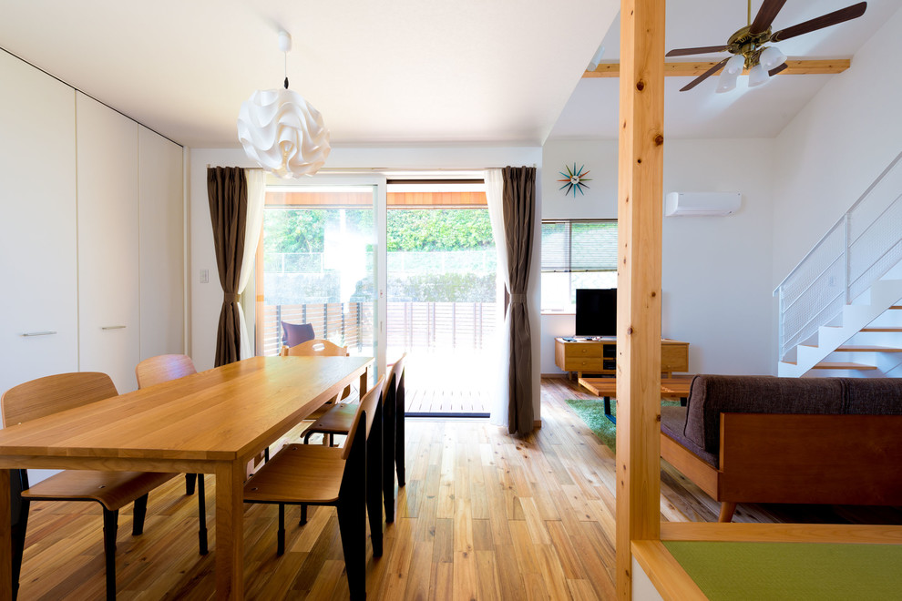 Imagen de comedor minimalista abierto con paredes blancas, suelo de madera en tonos medios y suelo marrón