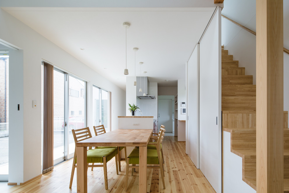 Diseño de comedor nórdico abierto con paredes blancas, suelo de madera clara y suelo beige