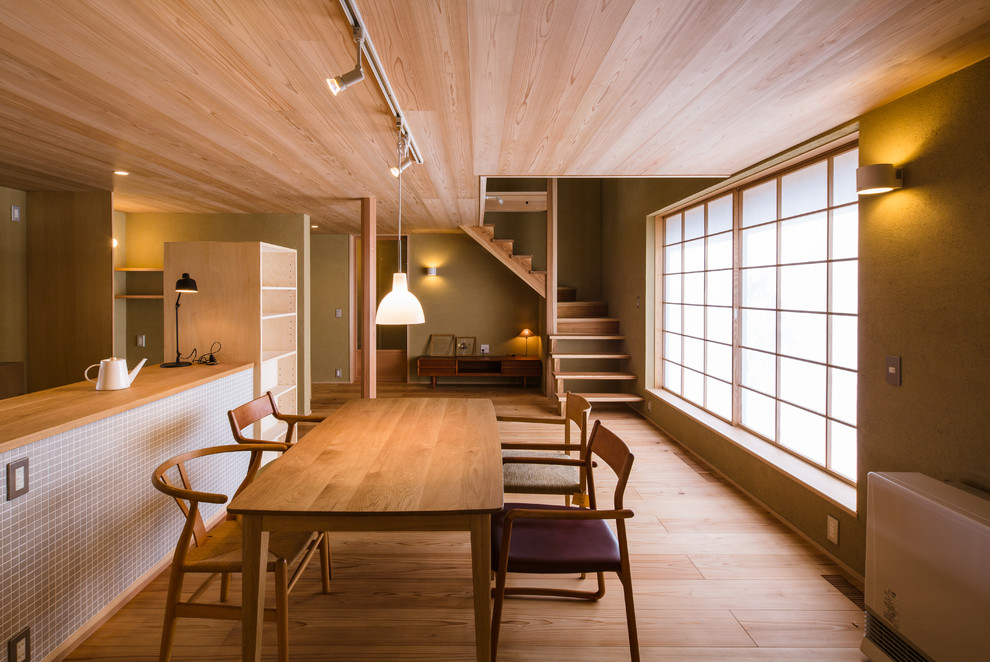 Foto di una sala da pranzo aperta verso il soggiorno etnica con pareti verdi, parquet chiaro e pavimento beige