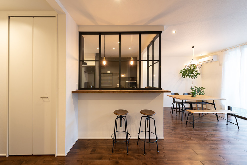 Idée de décoration pour une salle à manger ouverte sur le salon vintage avec un mur blanc, parquet foncé et un sol marron.