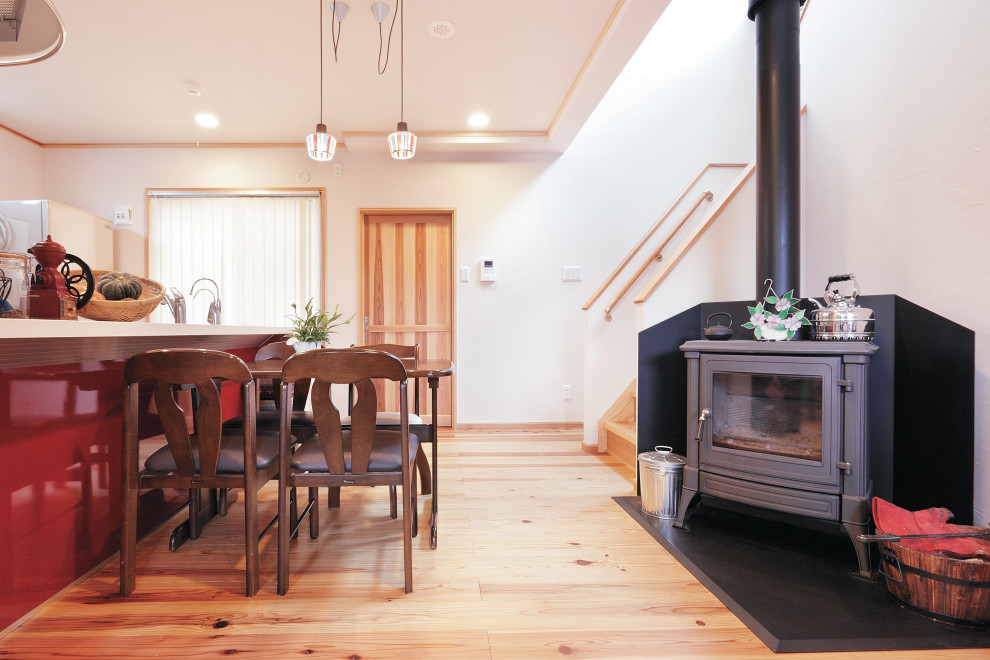 Ispirazione per una piccola sala da pranzo aperta verso il soggiorno minimalista con stufa a legna e cornice del camino in intonaco
