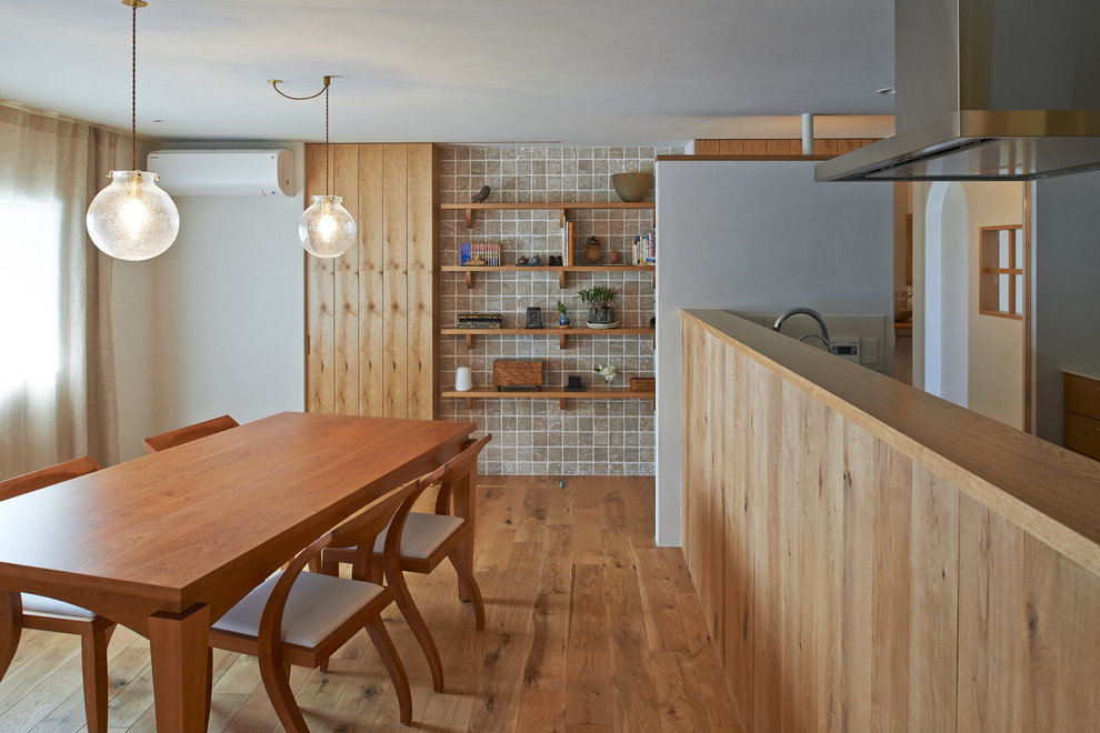 Immagine di una sala da pranzo aperta verso il soggiorno design con pareti bianche e pavimento in legno massello medio