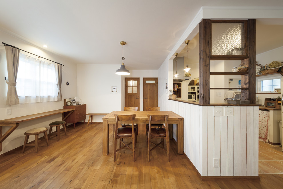Aménagement d'une salle à manger ouverte sur le salon campagne de taille moyenne avec un mur blanc, un sol en bois brun et un sol marron.