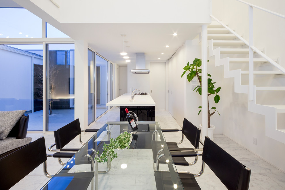 Immagine di una sala da pranzo aperta verso il soggiorno moderna con pareti bianche, pavimento grigio, pavimento in compensato e nessun camino