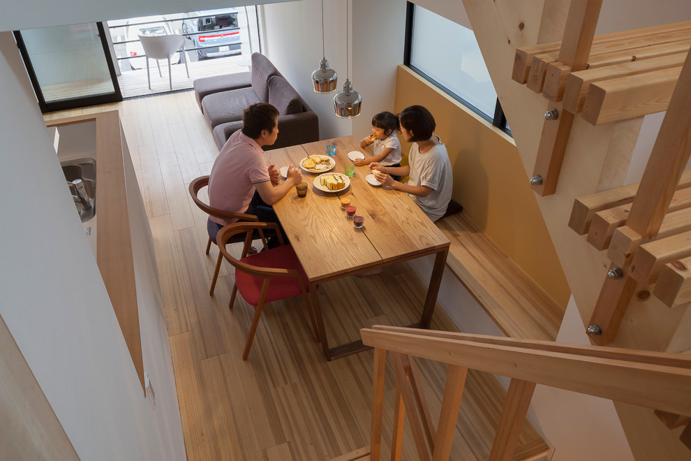 Cette image montre une salle à manger ouverte sur le salon asiatique avec un mur blanc, un sol en bois brun et aucune cheminée.