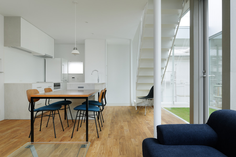 Ispirazione per una sala da pranzo aperta verso il soggiorno moderna con pareti bianche, pavimento in legno massello medio e pavimento beige