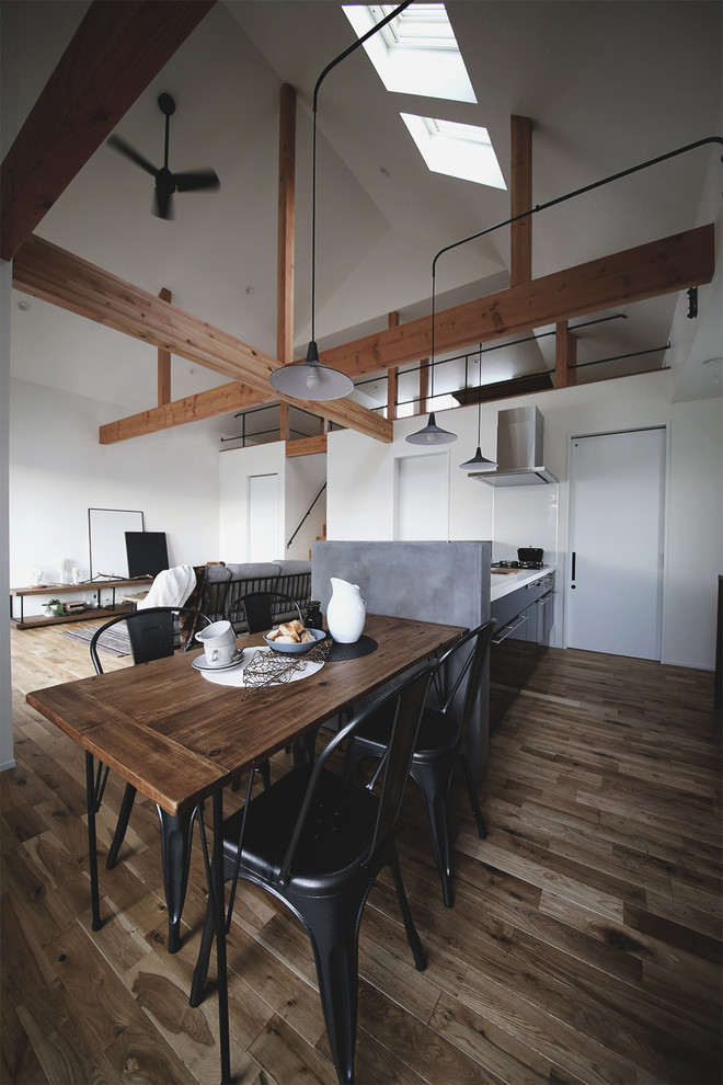 Idee per una sala da pranzo aperta verso il soggiorno industriale con pareti bianche, parquet scuro e pavimento marrone