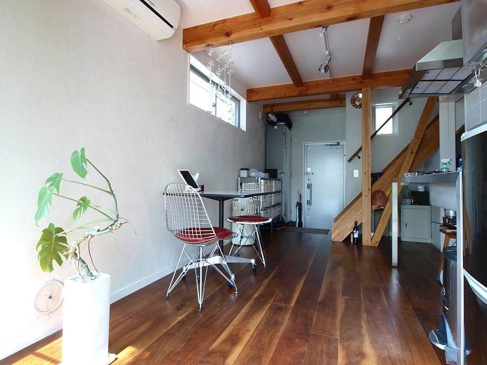 Foto di una sala da pranzo aperta verso la cucina industriale con pareti bianche, parquet scuro e pavimento marrone