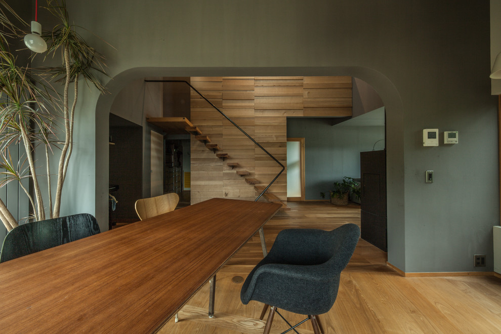 Réalisation d'une salle à manger ouverte sur le salon design avec un mur vert, un sol en bois brun et un sol marron.