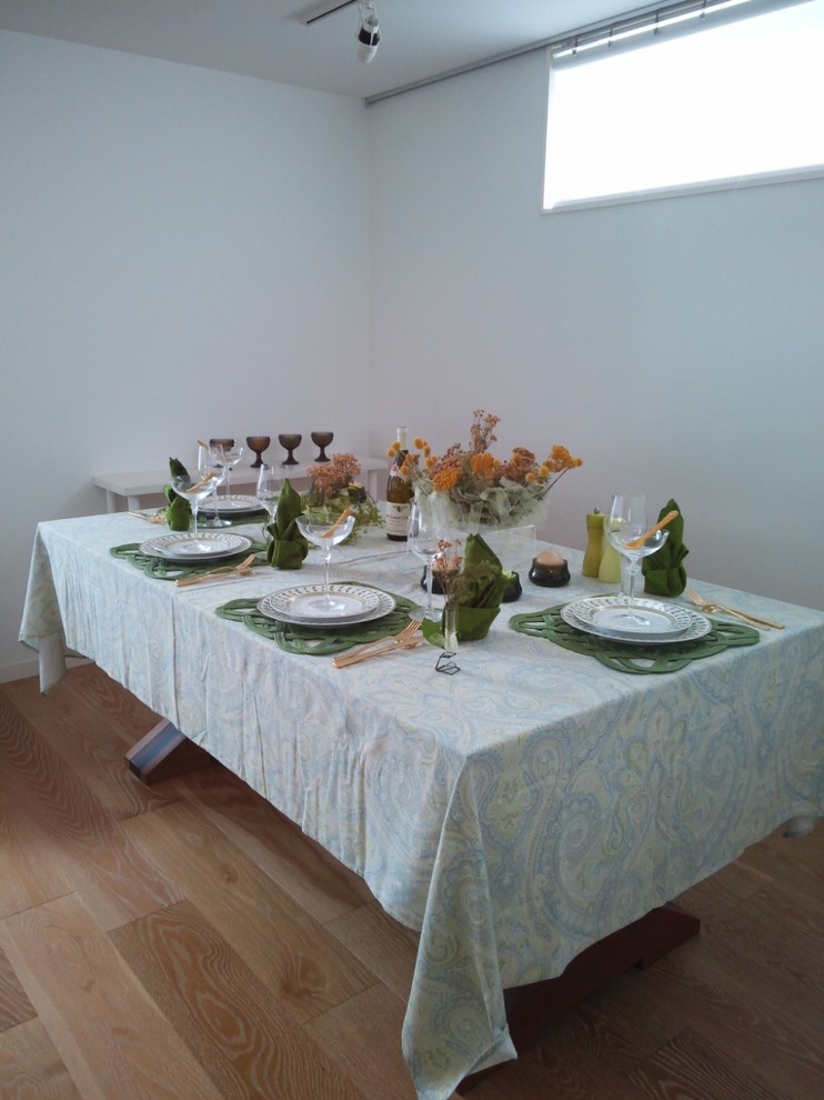Immagine di una sala da pranzo aperta verso il soggiorno con pareti bianche e parquet chiaro