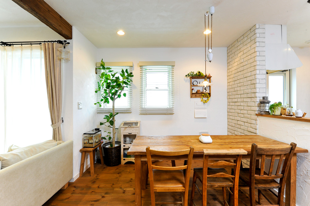 Ispirazione per una sala da pranzo aperta verso il soggiorno mediterranea con pareti bianche, pavimento in legno massello medio e pavimento marrone