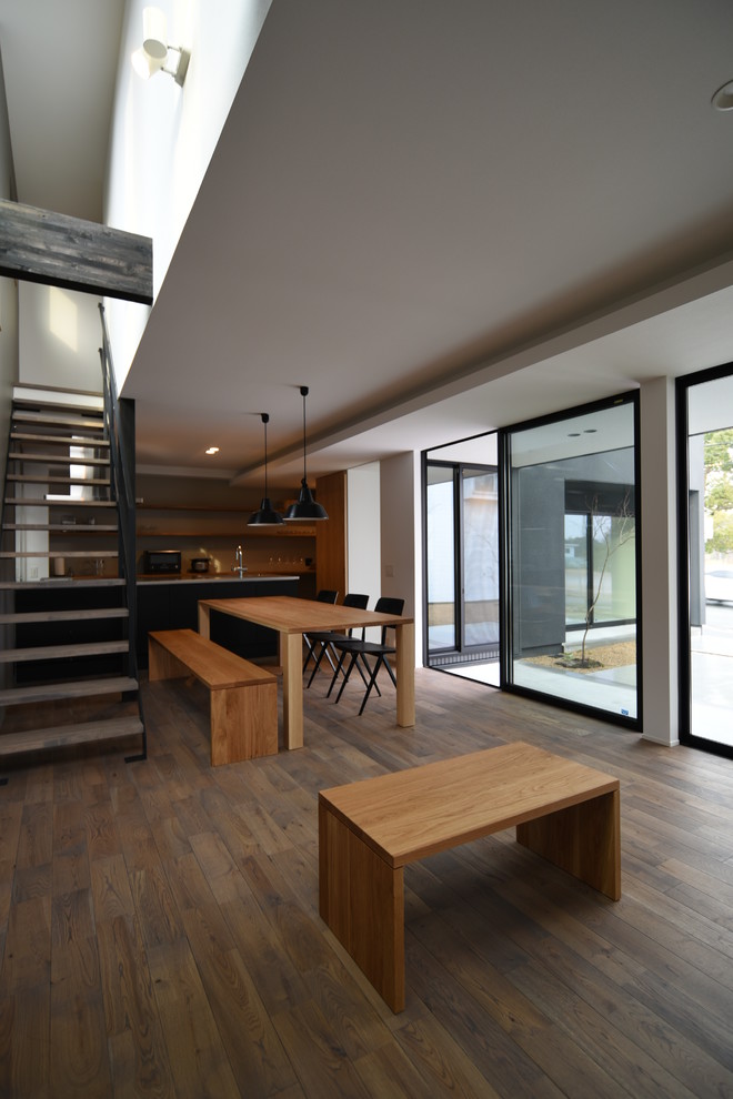 Ispirazione per una sala da pranzo aperta verso il soggiorno moderna con pareti bianche, pavimento in legno verniciato e pavimento marrone