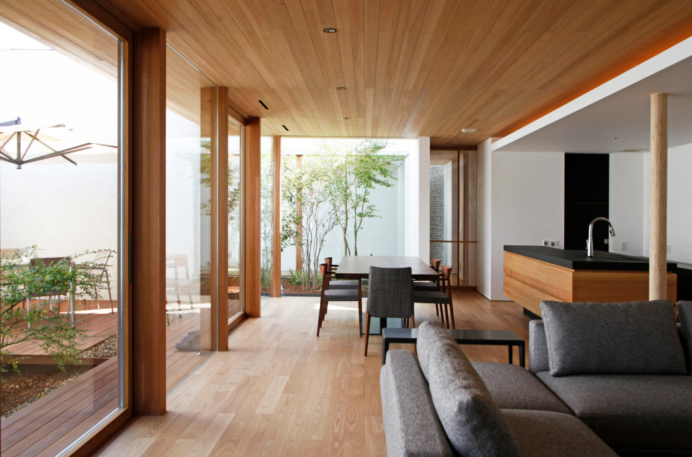 Modernes Esszimmer mit weißer Wandfarbe, braunem Holzboden, braunem Boden, Kaminofen und gefliester Kaminumrandung in Nagoya
