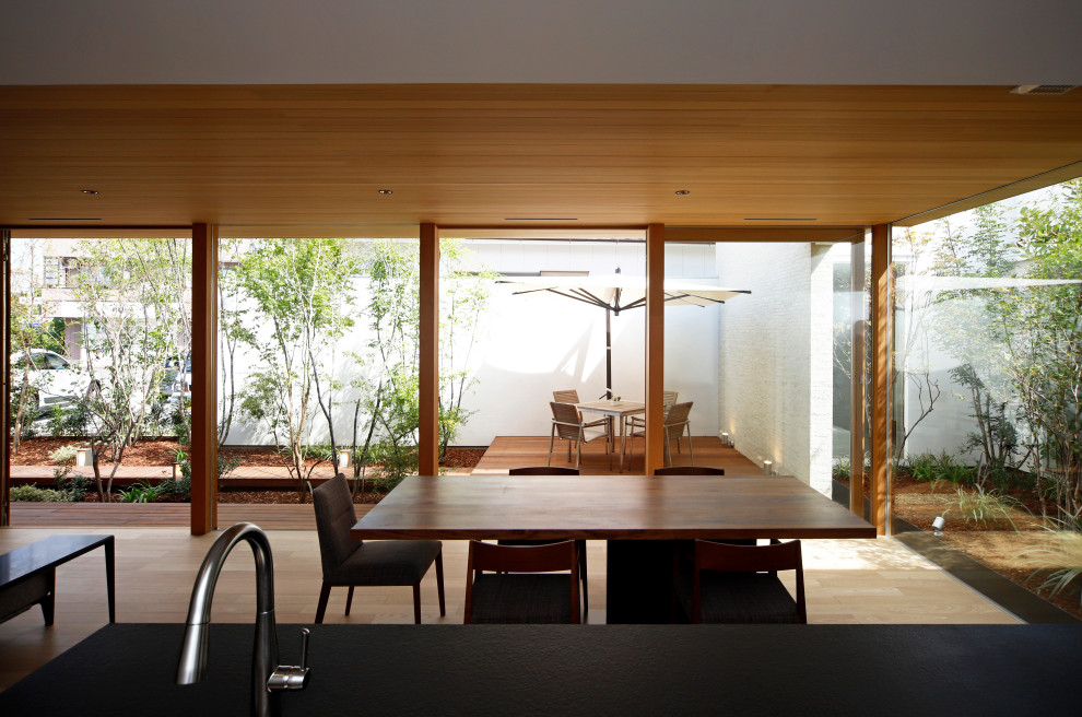 Esempio di una sala da pranzo minimalista con pareti bianche, pavimento in legno massello medio, stufa a legna, cornice del camino piastrellata e pavimento marrone