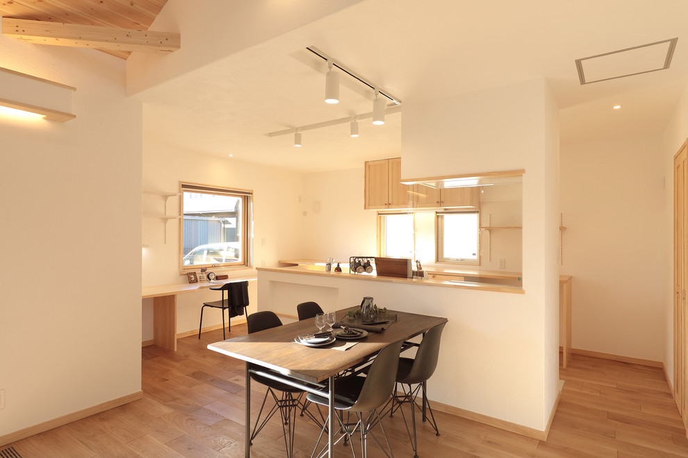 Cette photo montre une salle à manger ouverte sur le salon moderne avec un mur blanc, un sol en bois brun, aucune cheminée et un sol marron.