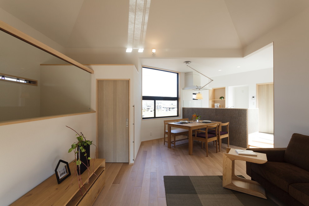 Immagine di una sala da pranzo aperta verso il soggiorno scandinava con pareti bianche, pavimento in legno massello medio e pavimento marrone