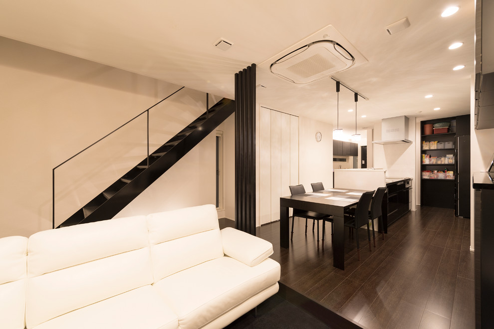 Immagine di una sala da pranzo aperta verso il soggiorno minimalista di medie dimensioni con pareti bianche e pavimento in compensato